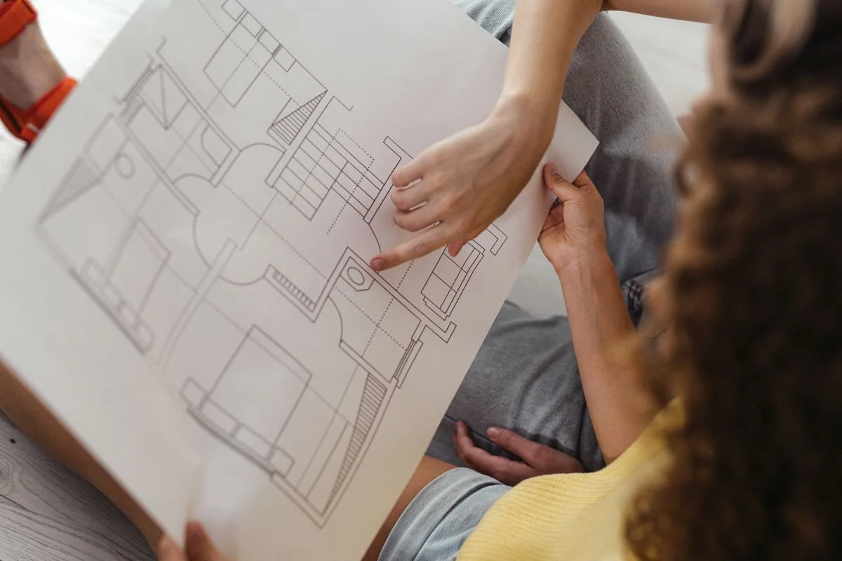 Real photograph of people reviewing a floor plan, used illustratively