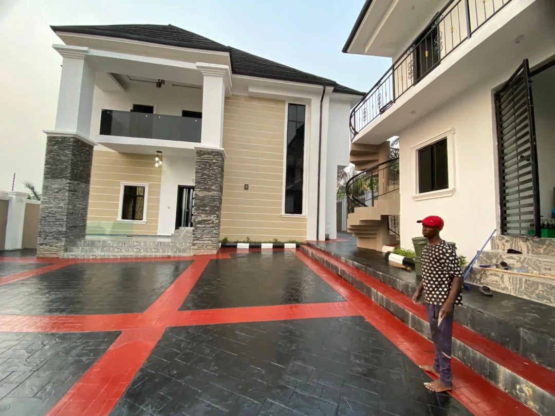 Wide view of the completed residence, adjoining building and paved compound